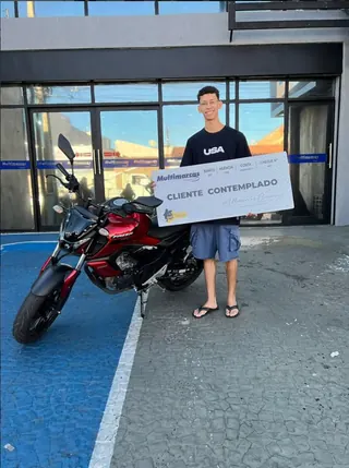 Cliente contemplado nº 3 pelo consórcio, segurando o cheque simbólico da carta de crédito