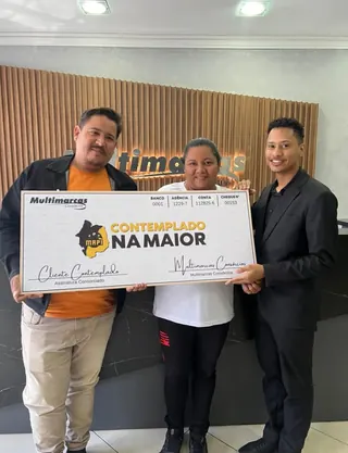Cliente contemplado nº 5 pelo consórcio, segurando o cheque simbólico da carta de crédito