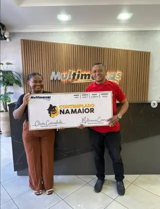 Cliente contemplado nº 7 pelo consórcio, segurando o cheque simbólico da carta de crédito