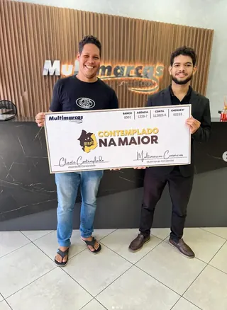 Cliente contemplado nº 8 pelo consórcio, segurando o cheque simbólico da carta de crédito