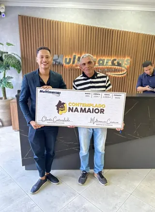 Cliente contemplado nº 9 pelo consórcio, segurando o cheque simbólico da carta de crédito