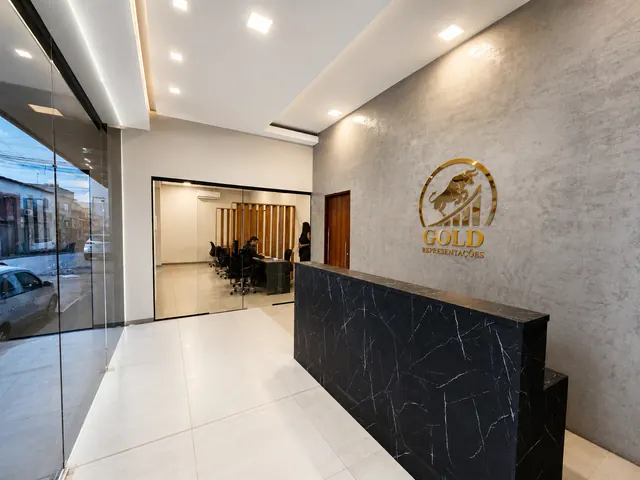 Recepção da Gold Representações: balcão em mármore preto e o logo do touro dourado na parede